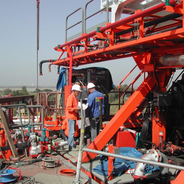 Panneau d'avertissement électrique fixé à une clôture métallique dans une zone industrielle, représentant un danger de haute tension. Control Safe Energy.